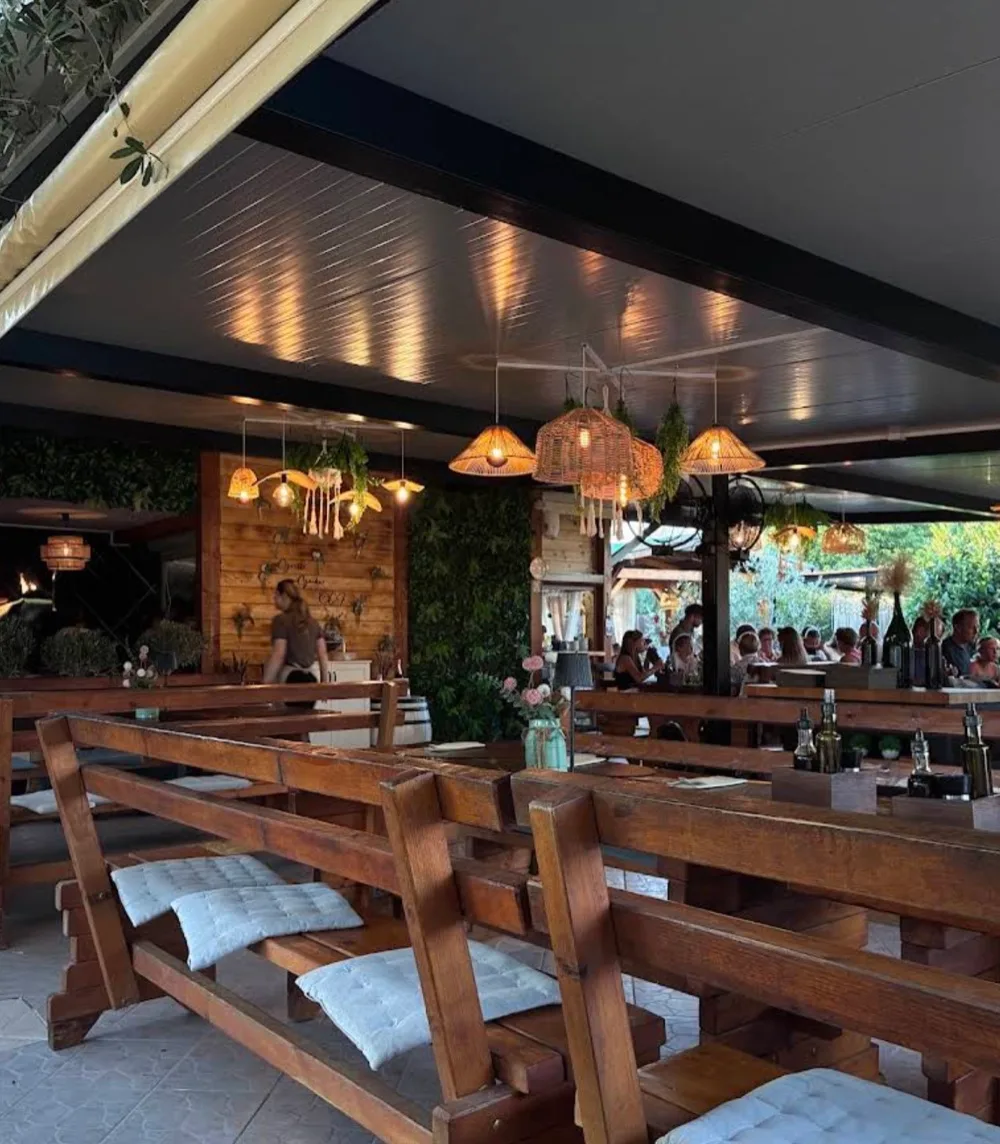 Covered garden terrace with wooden tables and woven pendant lights